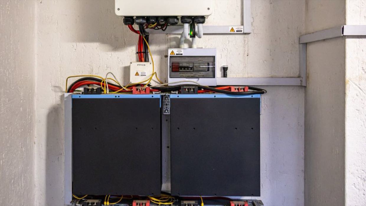 Wall-mounted battery storage units wired to an inverter and breaker board.