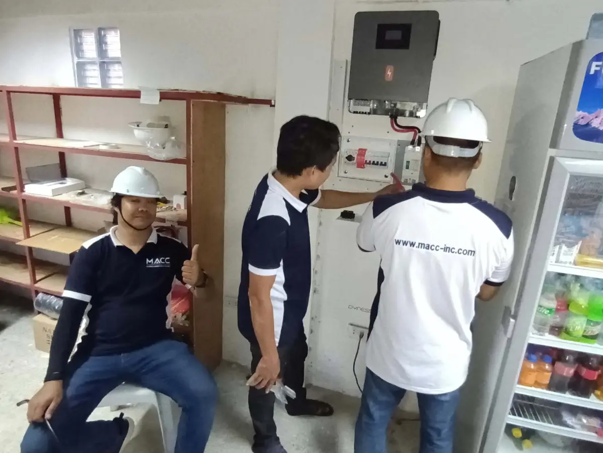 MACC team connecting the inverter, breakers and battery on an indoor wall